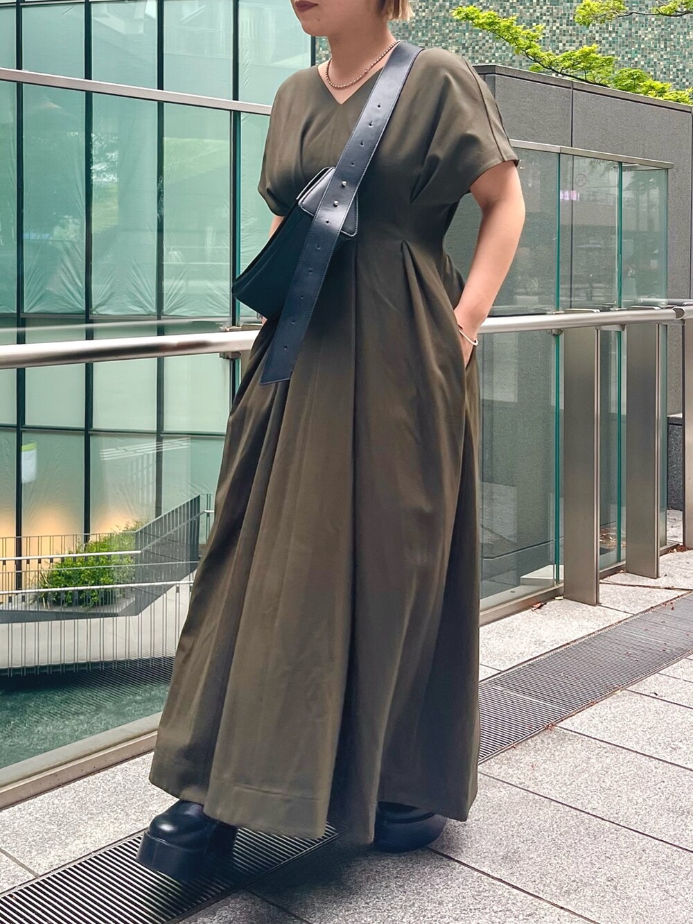 グリーン系のワンピース、ブラック系のブーツ、ブラック系のショルダーバッグを着用したレディースの春コーディネートの3枚目の写真