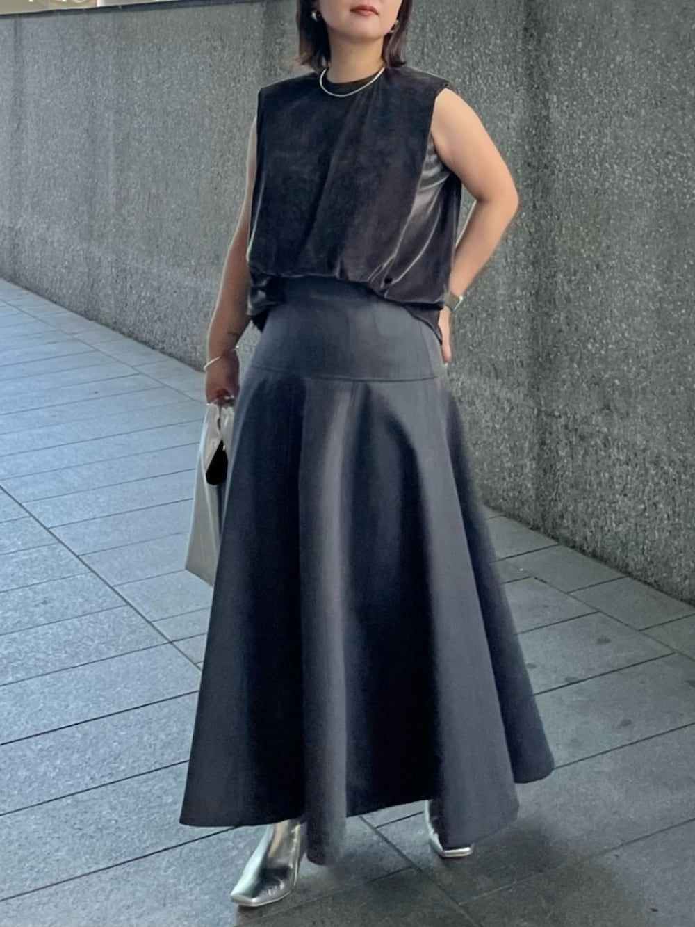 グレー系のスカート、ゴールド系のハンドバッグ、グレー系のTシャツ/カットソーを着用したレディースの夏コーディネートの4枚目の写真