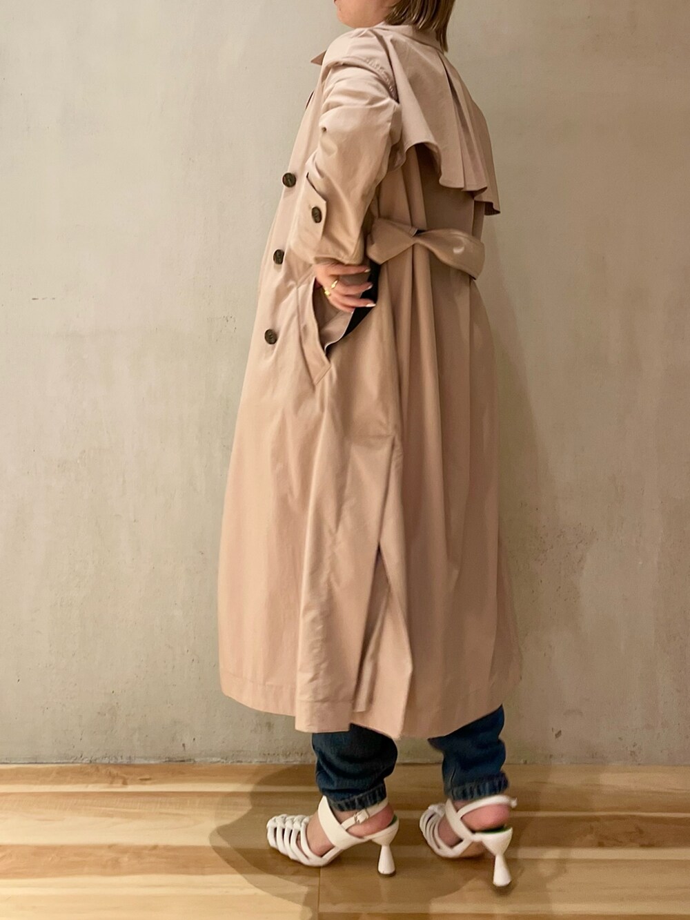 グリーン系のニット/セーター、ベージュ系のトレンチコート、ブルー系のデニムパンツを着用したレディースの冬コーディネートの2枚目の写真