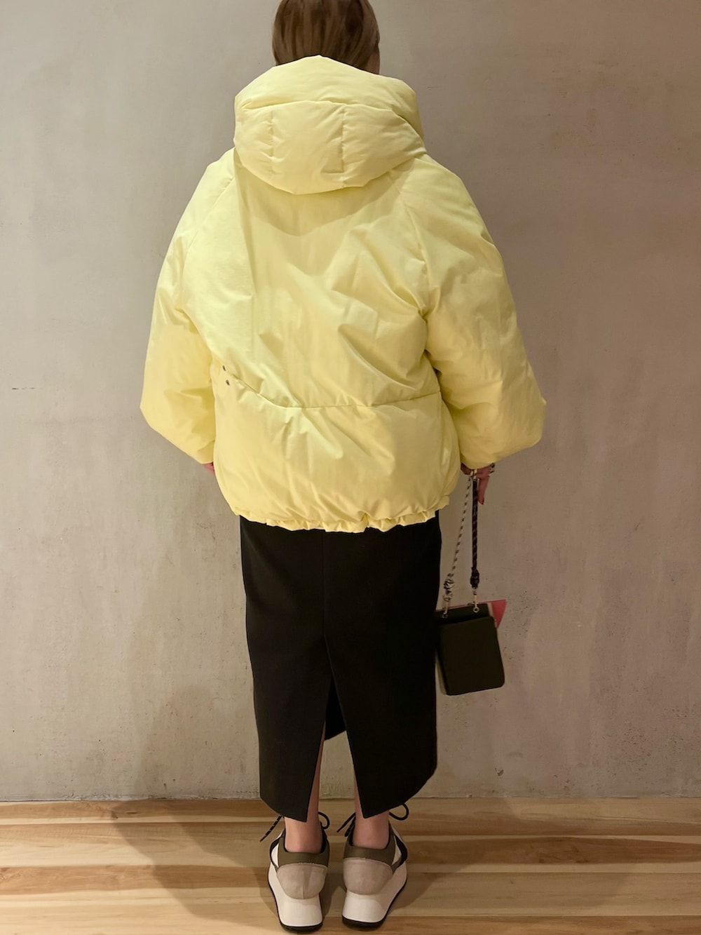 イエロー系のダウンジャケット/コート、グレー系のニット/セーター、ベージュ系のショルダーバッグを着用したレディースの冬コーディネートの3枚目の写真