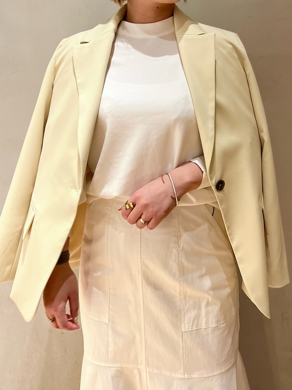 イエロー系のテーラードジャケット、ホワイト系のニット/セーター、ホワイト系のスカートを着用したレディースの冬コーディネートの5枚目の写真