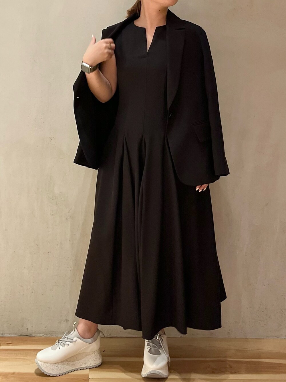 ブラック系のテーラードジャケット、ブラック系のワンピース、ホワイト系のスニーカーを着用したレディースの冬コーディネートの3枚目の写真