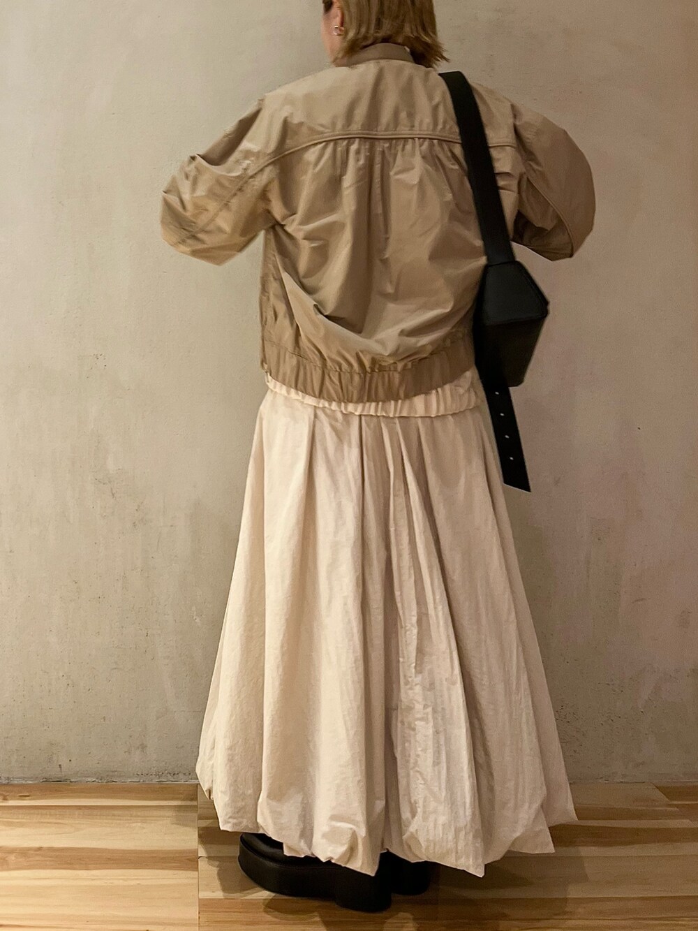 ベージュ系のブルゾン、ベージュ系のワンピース、ブラック系のブーツを着用したレディースの夏コーディネートの3枚目の写真