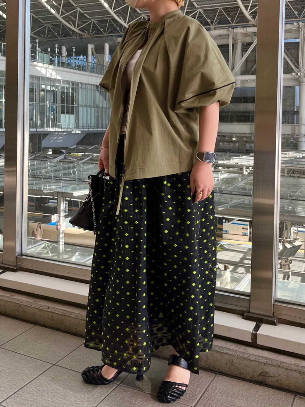 グリーン系のブルゾン、ホワイト系のタンクトップ、その他のスカートを着用したレディースの春コーディネートの3枚目の写真