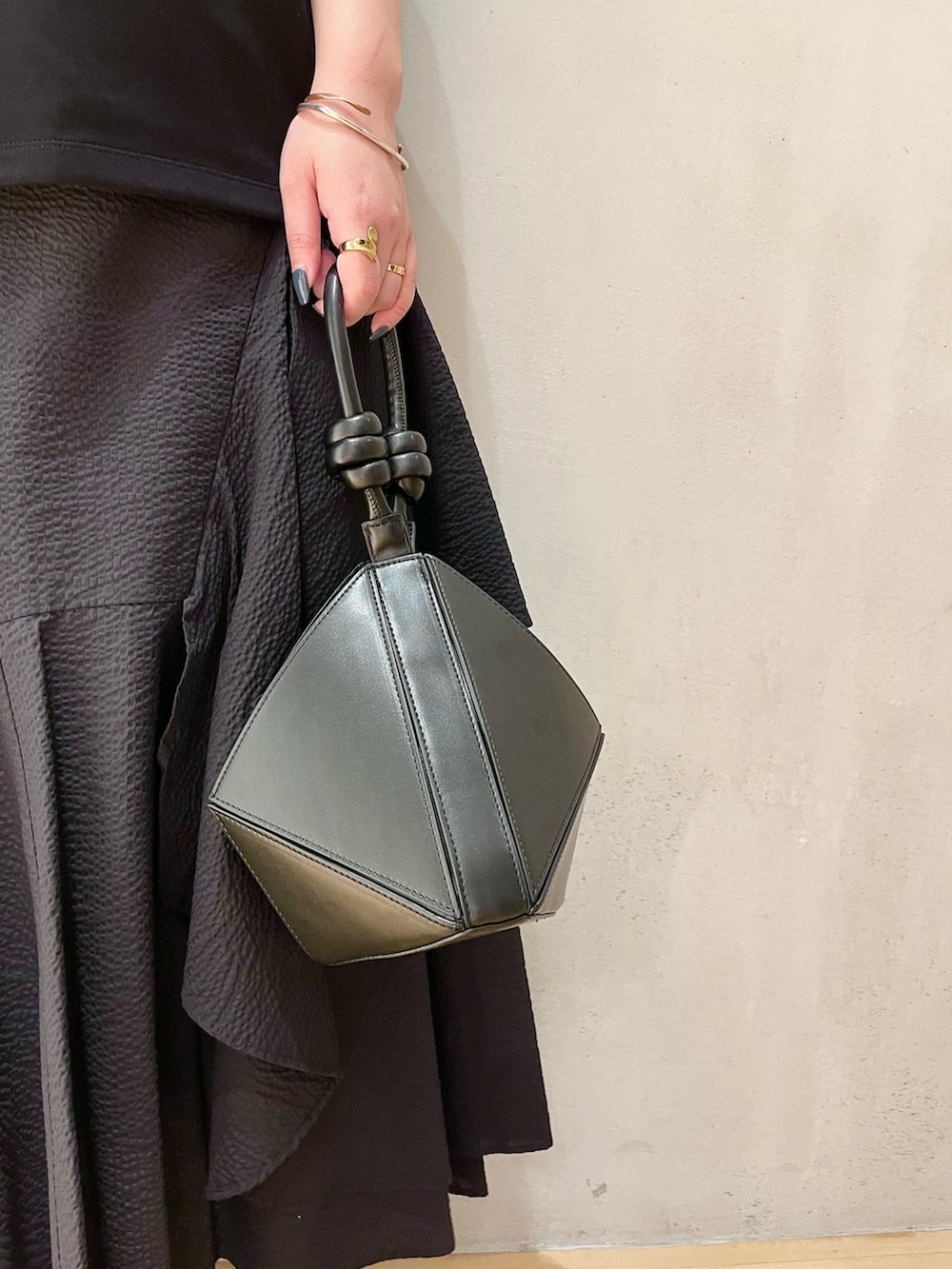 ブラック系のTシャツ/カットソー、ブラック系のスカート、ブラック系のハンドバッグを着用したレディースの春コーディネートの9枚目の写真