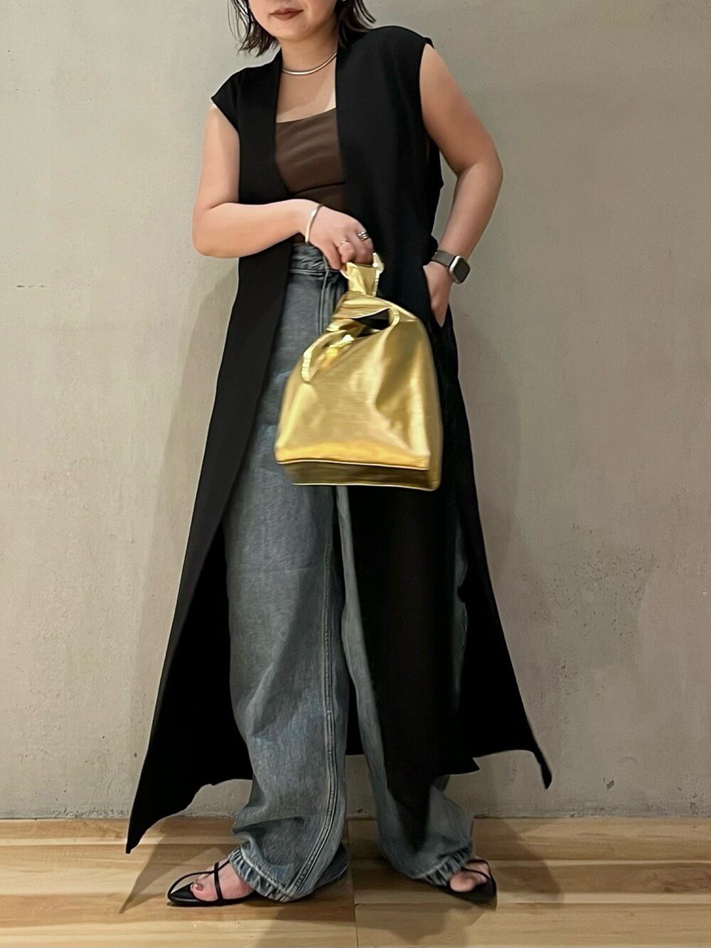 ブラック系のベスト、ブラウン系のタンクトップ、ブルー系のデニムパンツを着用したレディースの夏コーディネートの4枚目の写真