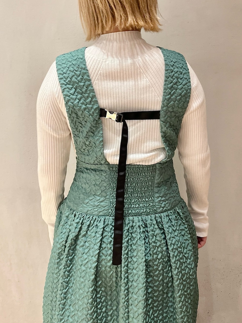 ブラック系のノーカラージャケット、グリーン系のジャンパースカート、ホワイト系のニット/セーターを着用したレディースの秋コーディネートの8枚目の写真