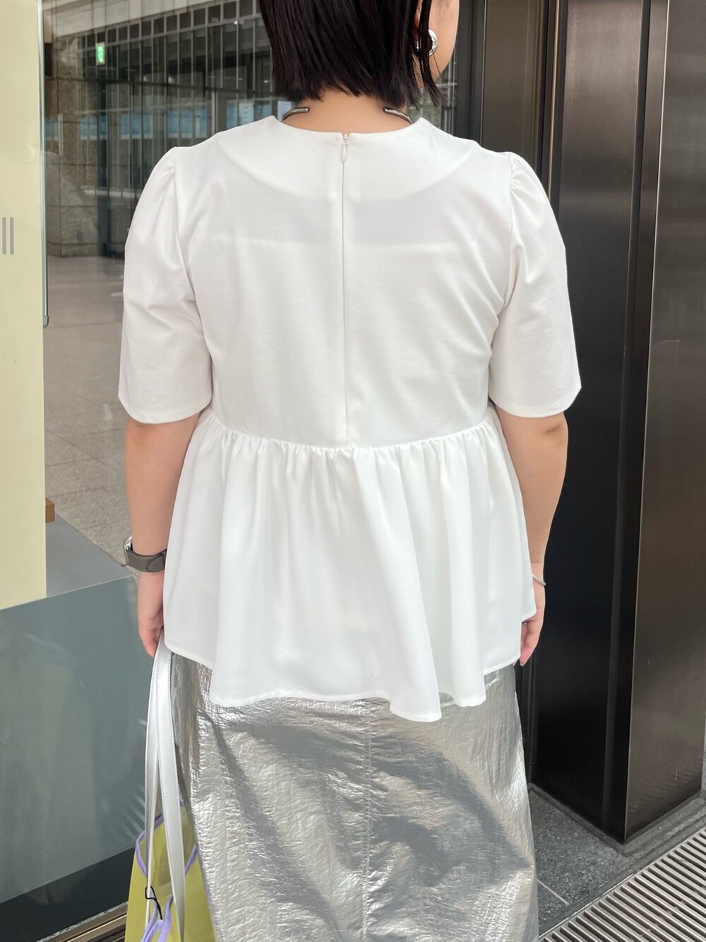 ホワイト系のTシャツ/カットソー、シルバー系のスカート、イエロー系のトートバッグを着用したレディースの春コーディネートの7枚目の写真