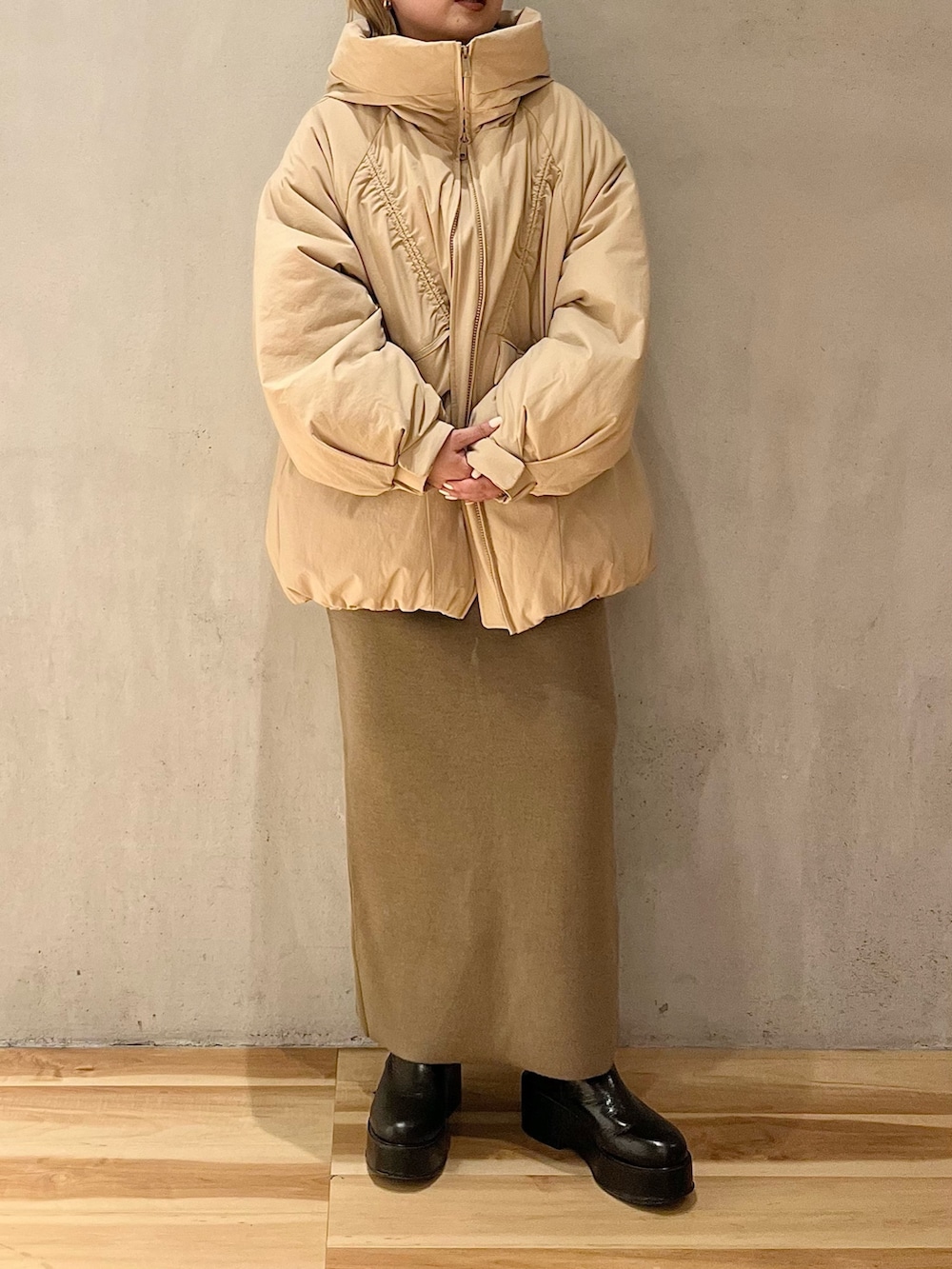 ベージュ系のダウンジャケット/コート、ベージュ系のスカート、ベージュ系のニット/セーターを着用したレディースの冬コーディネートの2枚目の写真