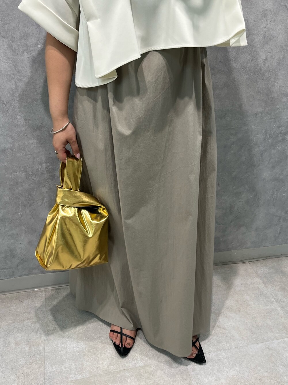 ベージュ系のワンピース、ゴールド系のハンドバッグを着用したレディースの夏コーディネートの9枚目の写真