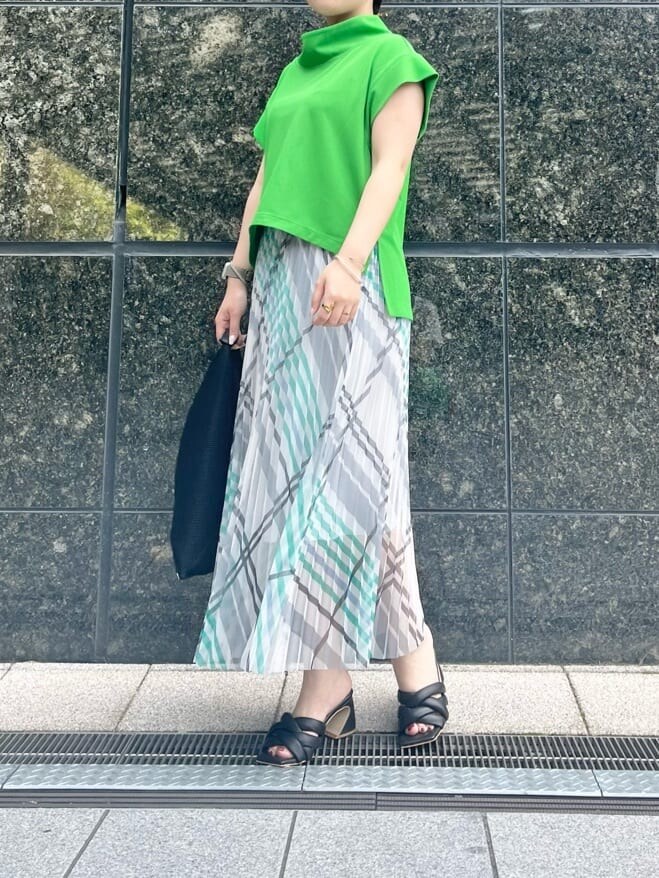 ブラック系のサンダル、グリーン系のTシャツ/カットソー、ホワイト系のスカートを着用したレディースの春コーディネートの2枚目の写真
