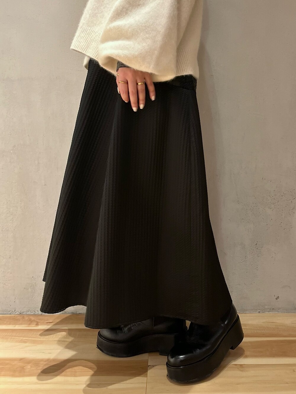 ホワイト系のニット/セーター、シルバー系のTシャツ/カットソー、ブラック系のスカートを着用したレディースの冬コーディネートの9枚目の写真