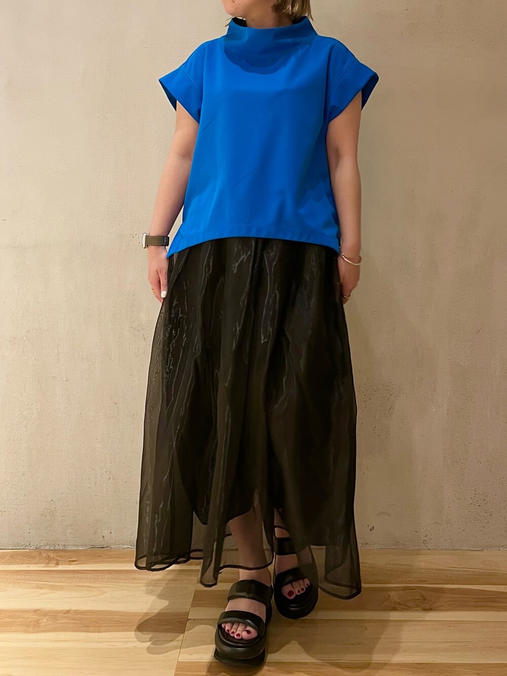 ブルー系のTシャツ/カットソー、ブラック系のスカート、ブラック系のサンダルを着用したレディースの冬コーディネートの4枚目の写真