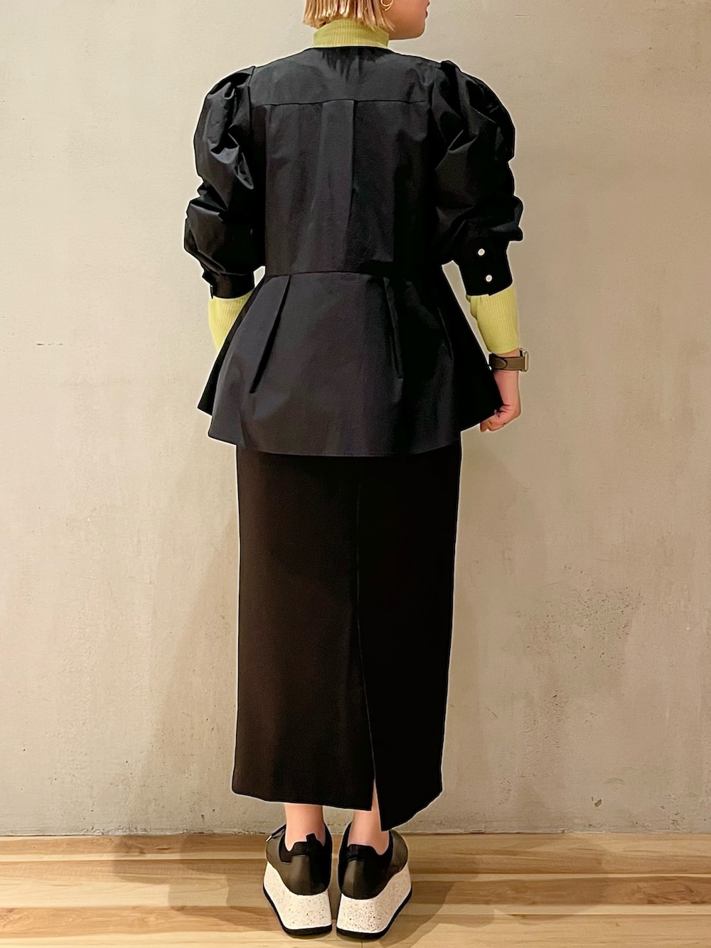 ブラック系のシャツ/ブラウス、グリーン系のニット/セーター、ブラック系のスカートを着用したレディースの冬コーディネートの2枚目の写真