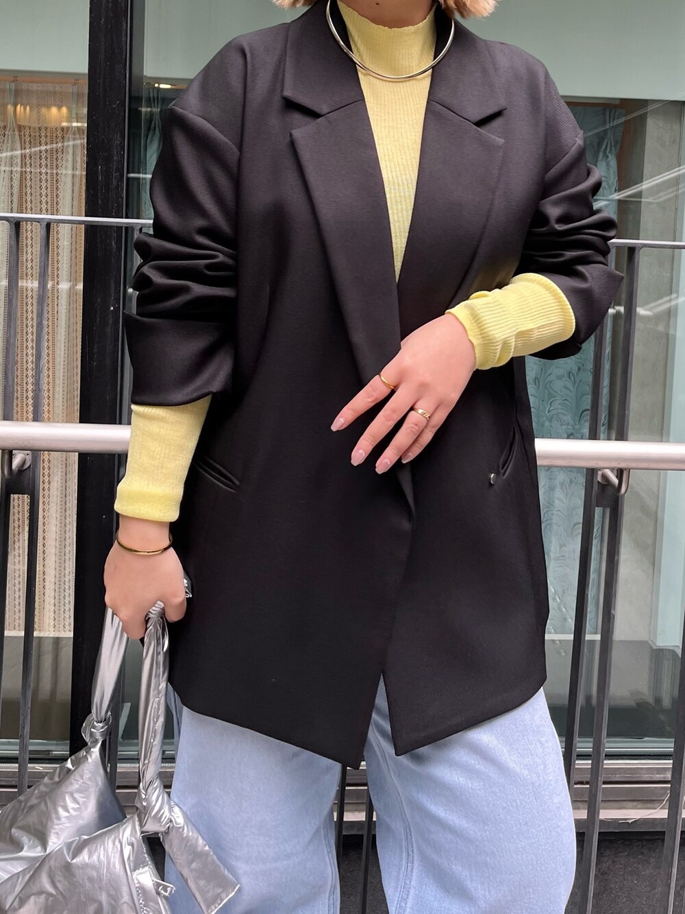 ブラック系のテーラードジャケット、イエロー系のニット/セーター、ブルー系のデニムパンツを着用したレディースの冬コーディネートの6枚目の写真