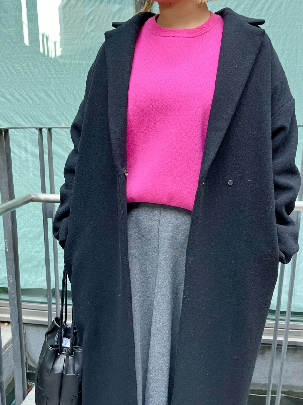 ピンク系のニット/セーター、ブラック系のチェスターコート、グレー系のスカートを着用したレディースの冬コーディネートの7枚目の写真