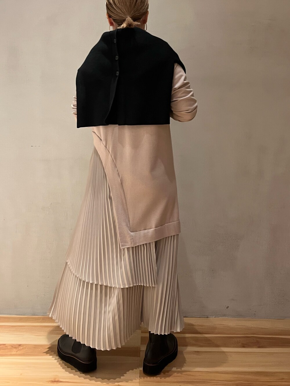 グリーン系のチェスターコート、ブラック系のカーディガン/ボレロ、ベージュ系のワンピースを着用したレディースの冬コーディネートの7枚目の写真