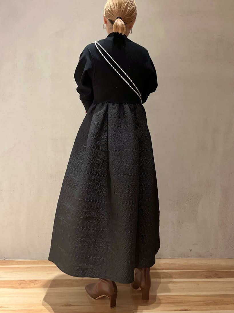 ベージュ系のショルダーバッグ、ブラウン系のブーツ、ブラック系のワンピースを着用したレディースの秋コーディネートの3枚目の写真