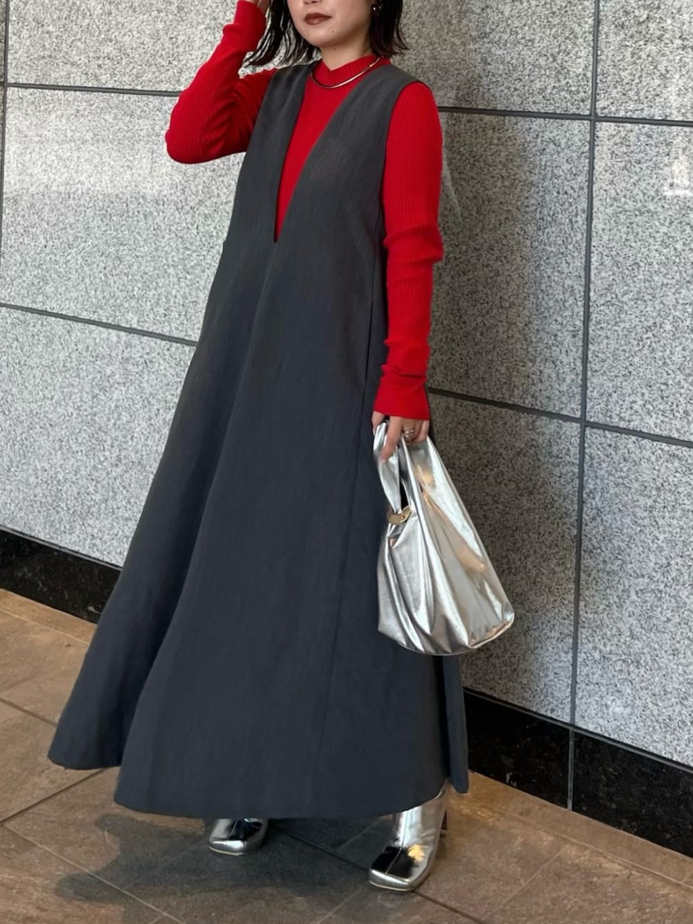 グレー系のジャンパースカート、シルバー系のブーツ、ゴールド系のハンドバッグを着用したレディースの夏コーディネートの2枚目の写真