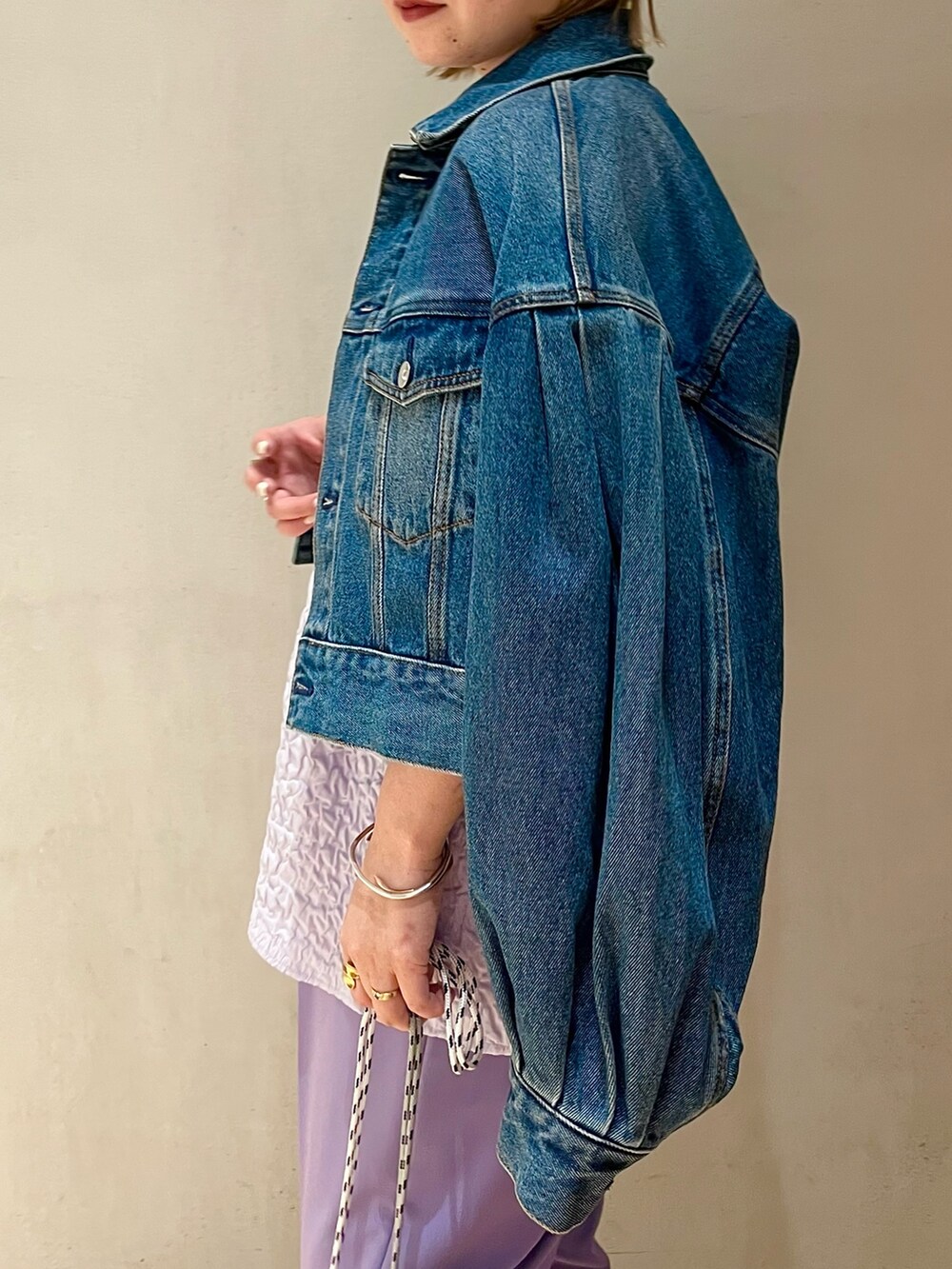 グレー系のショルダーバッグ、ブルー系のデニムジャケット、パープル系のその他パンツを着用したレディースの冬コーディネートの4枚目の写真