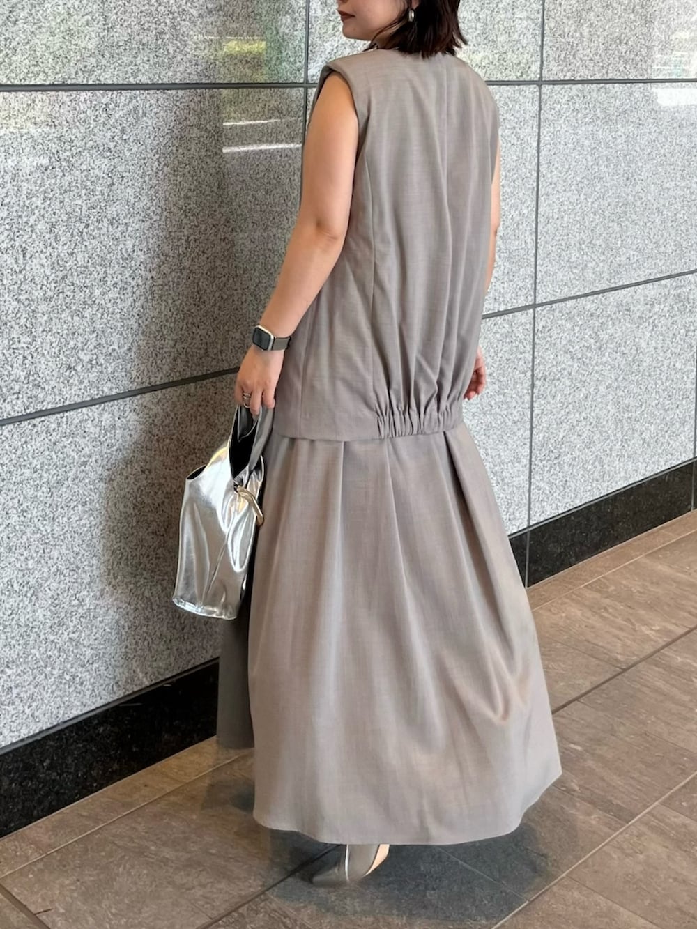 グレー系のワンピース、シルバー系のハンドバッグ、シルバー系のブーツを着用したレディースの夏コーディネートの6枚目の写真