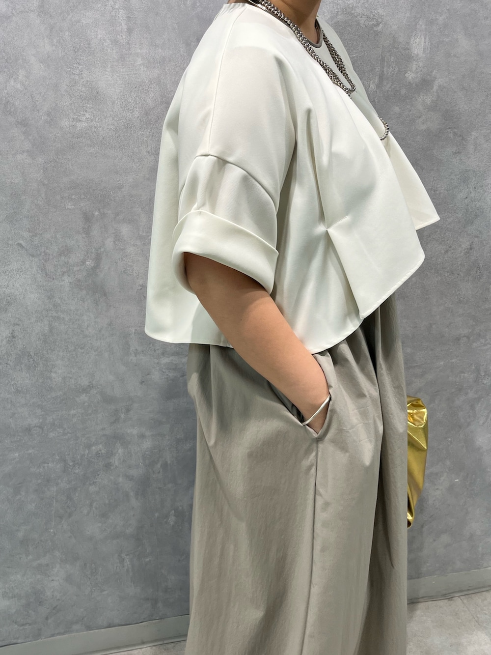 ベージュ系のワンピース、ゴールド系のハンドバッグを着用したレディースの夏コーディネートの7枚目の写真