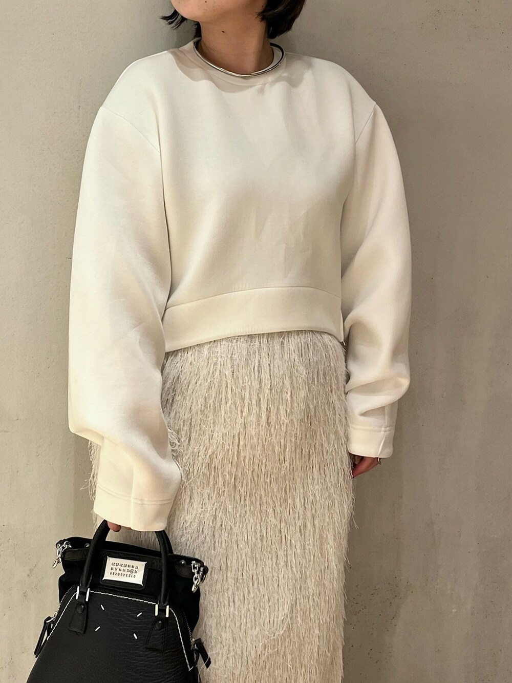 ホワイト系のTシャツ/カットソー、ホワイト系のスカート、ホワイト系のブーツを着用したレディースの春コーディネートの6枚目の写真