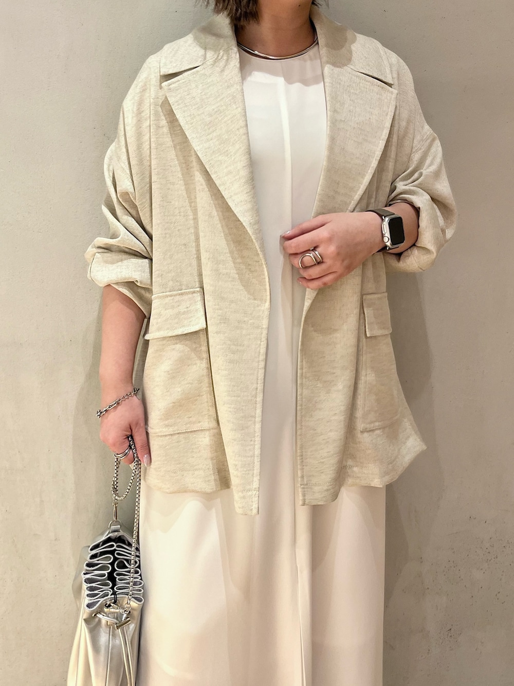 ベージュ系のテーラードジャケット、ホワイト系のワンピース、シルバー系のショルダーバッグを着用したレディースの春コーディネートの5枚目の写真