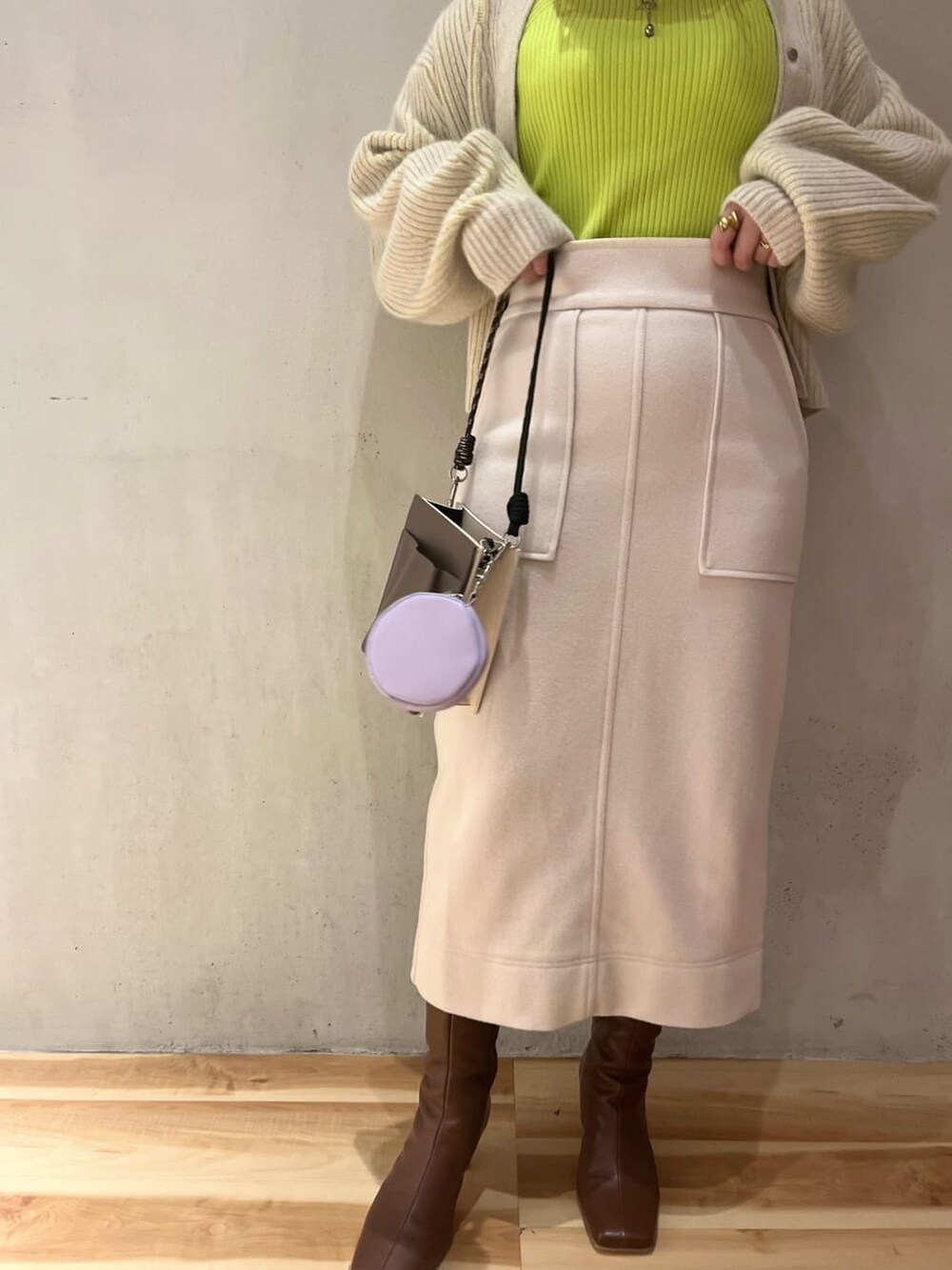 ブラウン系のブーツ、ベージュ系のショルダーバッグ、グリーン系のニット/セーターを着用したレディースの秋コーディネートの6枚目の写真