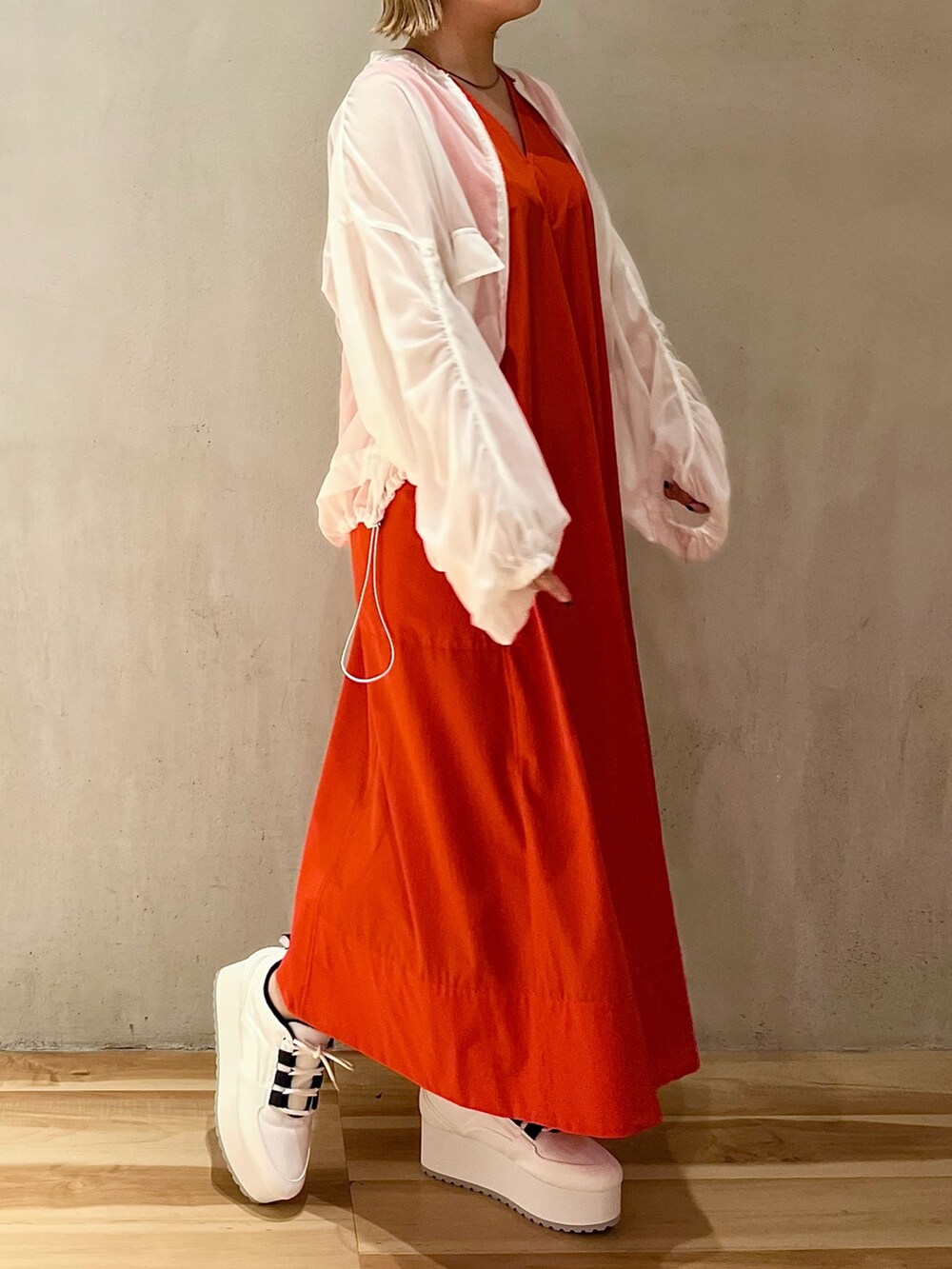 ホワイト系のブルゾン、レッド系のワンピース、ホワイト系のスニーカーを着用したレディースの夏コーディネートの3枚目の写真