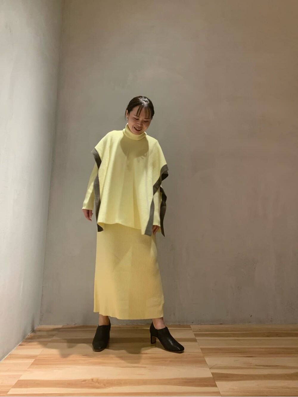 イエロー系のワンピース、ブラック系のブーツを着用したレディースの秋コーディネートの3枚目の写真