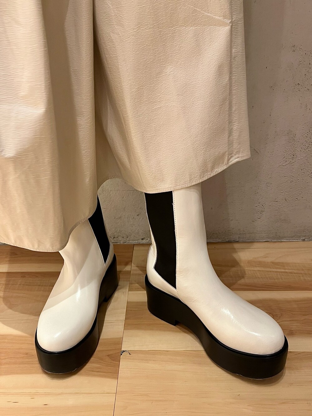 グリーン系のニット/セーター、ホワイト系のジャンパースカート、ホワイト系のブーツを着用したレディースの秋コーディネートの8枚目の写真