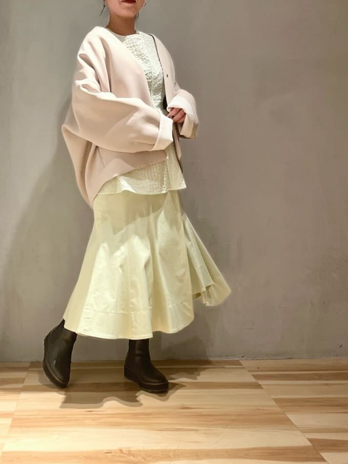 ベージュ系のステンカラーコート、グリーン系のスカート、グリーン系のシャツ/ブラウスを着用したレディースの春コーディネートの2枚目の写真