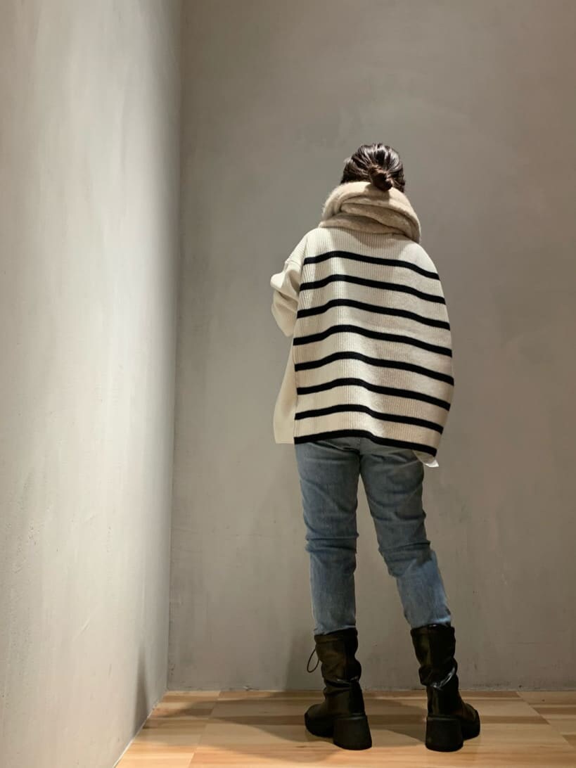 ブルー系のデニムパンツ、ブラック系のブーツ、ホワイト系のニット/セーターを着用したレディースの秋コーディネートの3枚目の写真