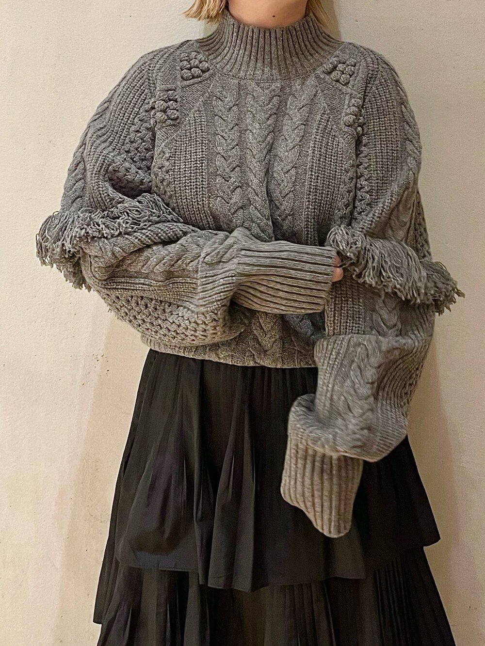 グレー系のニット/セーター、ブラック系のスカート、ブラック系のブーツを着用したレディースの秋コーディネートの5枚目の写真