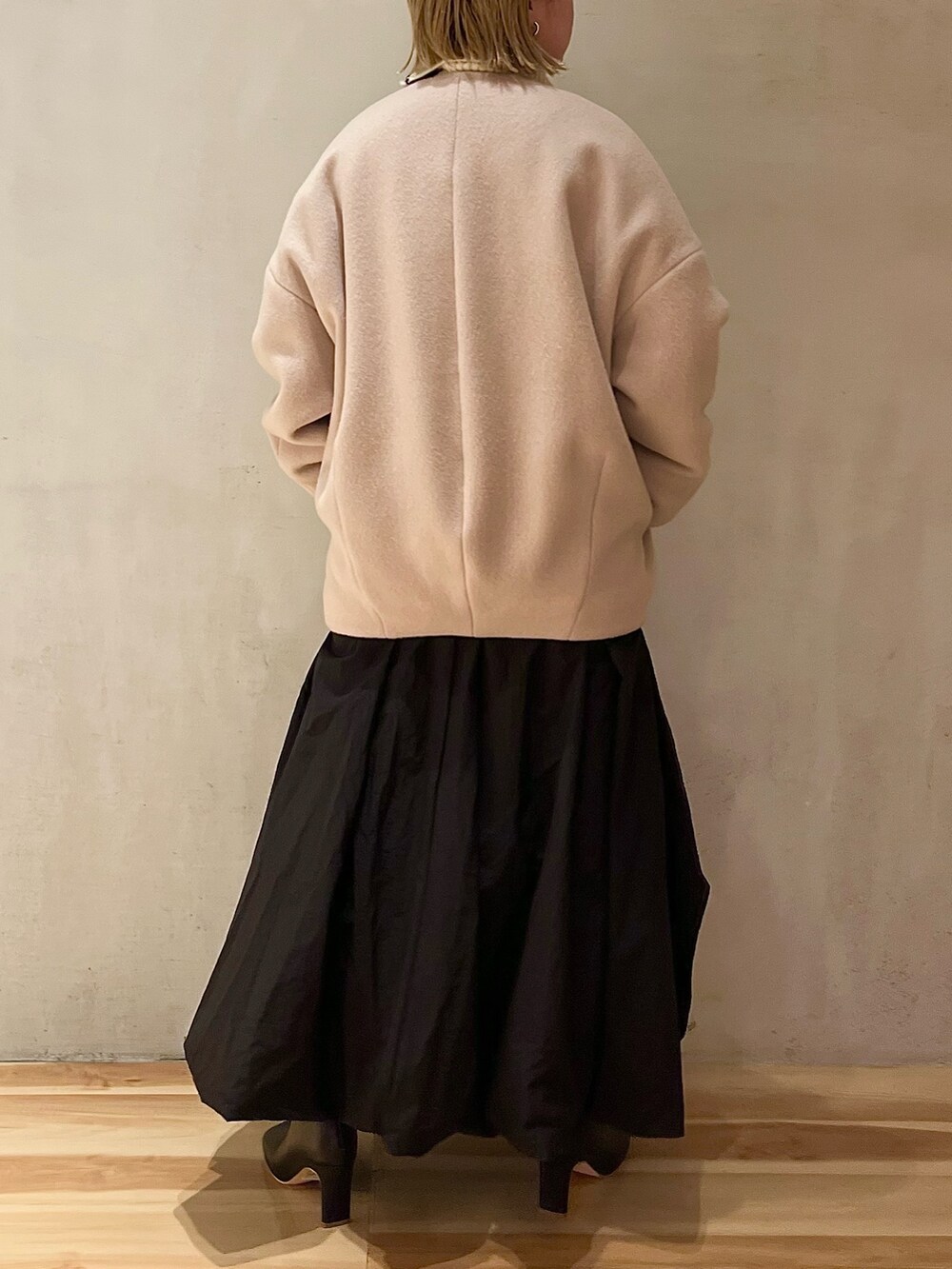 ベージュ系のノーカラーコート、ブラック系のスカート、ブラック系のブーツを着用したレディースの夏コーディネートの4枚目の写真