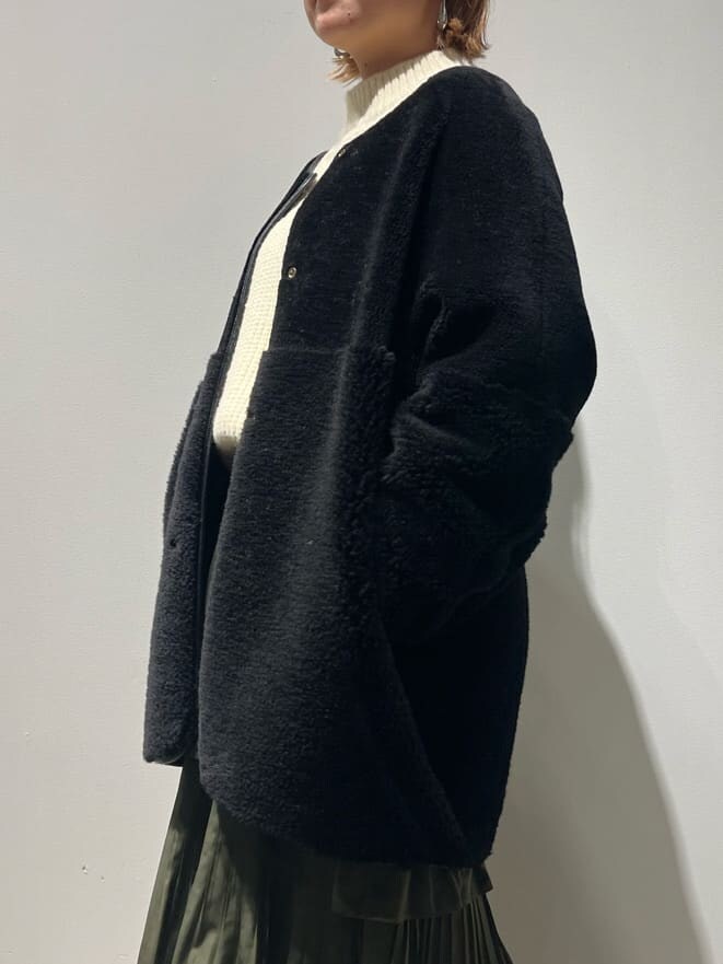 ブラック系のその他アウター、ホワイト系のニット/セーター、グリーン系のスカートを着用したレディースの秋コーディネートの4枚目の写真