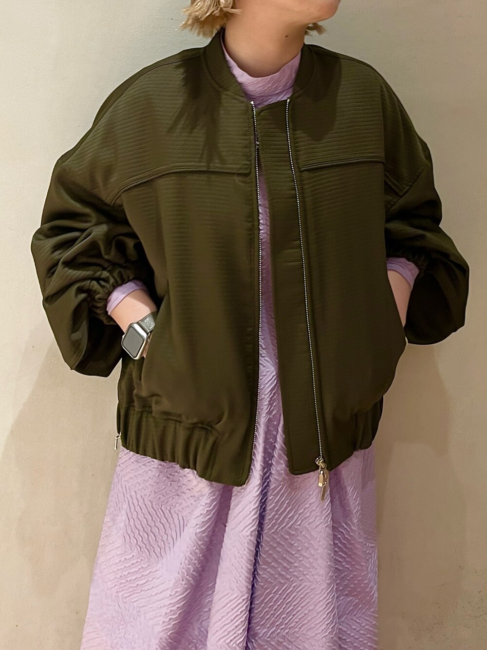 グリーン系のブルゾン、パープル系のワンピースを着用したレディースの春コーディネートの4枚目の写真