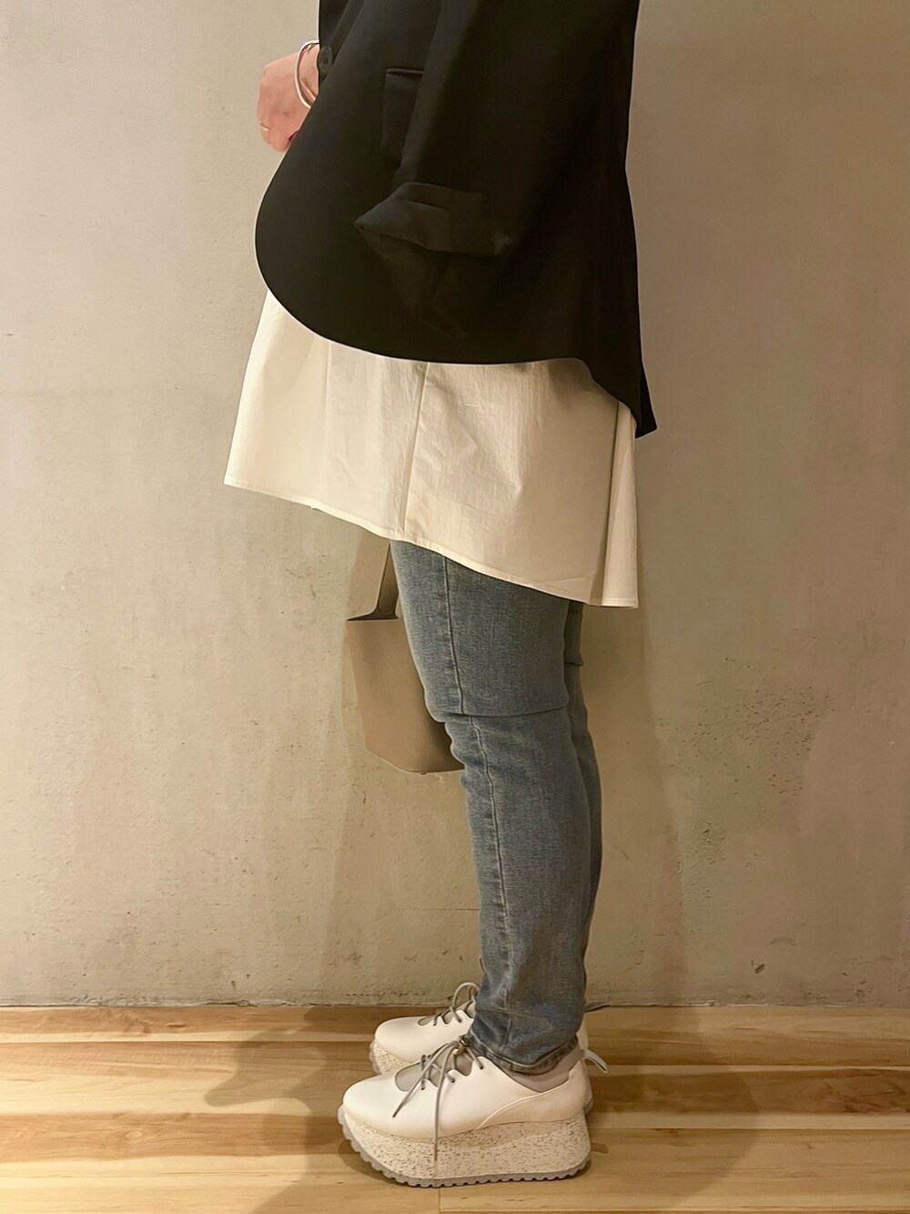 ブラック系のテーラードジャケット、ホワイト系のシャツ/ブラウス、ブルー系のデニムパンツを着用したレディースの冬コーディネートの9枚目の写真