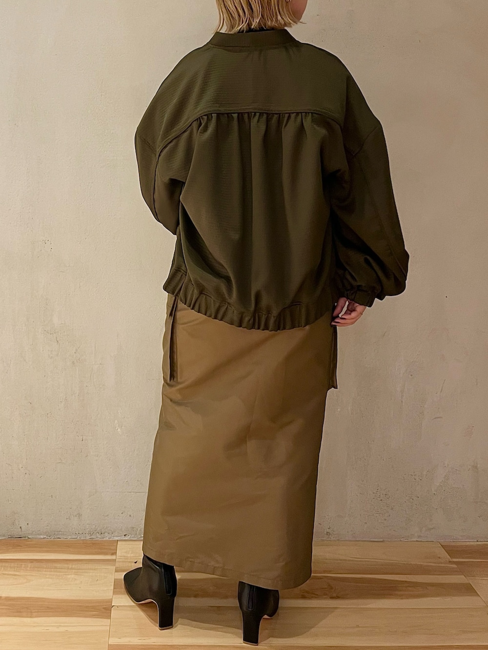 ブラウン系のスカート、ブラック系のブーツ、ブラック系のニット/セーターを着用したレディースの春コーディネートの3枚目の写真