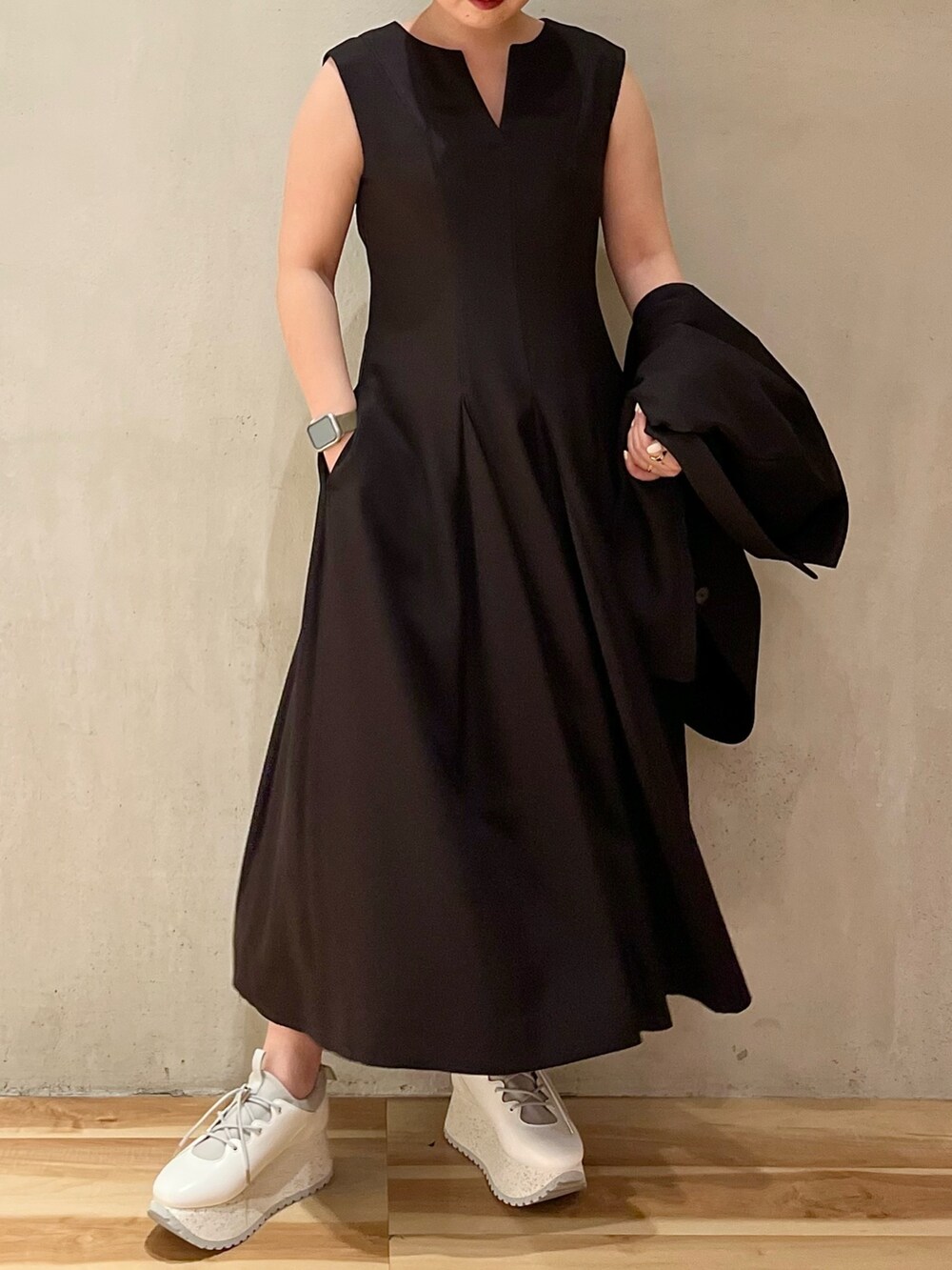 ブラック系のテーラードジャケット、ブラック系のワンピース、ホワイト系のスニーカーを着用したレディースの冬コーディネートの4枚目の写真