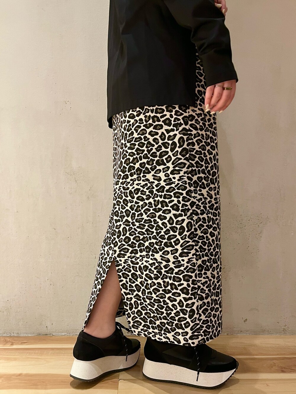 ブラック系のTシャツ/カットソー、ホワイト系のスカート、ブラック系のスニーカーを着用したレディースの春コーディネートの8枚目の写真