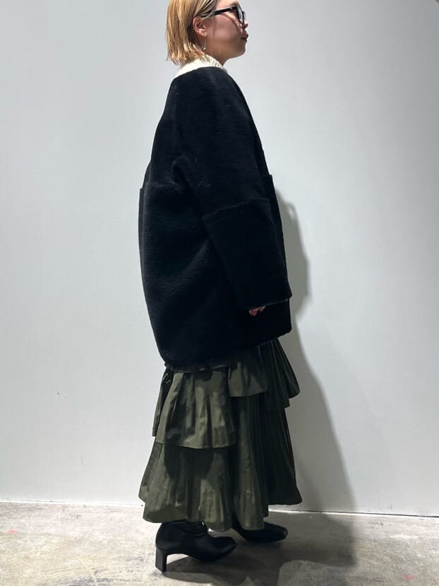 ブラック系のその他アウター、ホワイト系のニット/セーター、グリーン系のスカートを着用したレディースの秋コーディネートの2枚目の写真