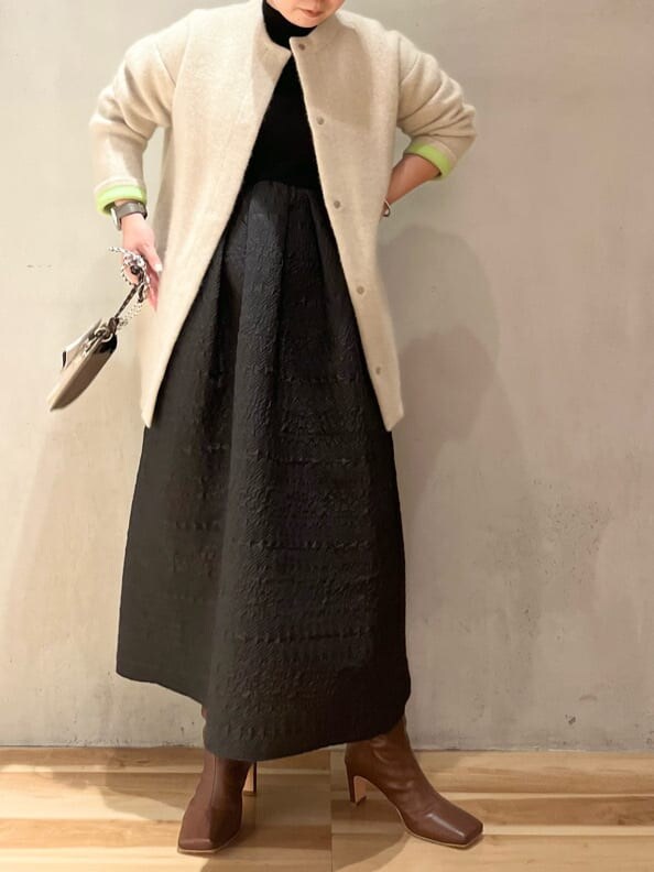 ベージュ系のショルダーバッグ、ホワイト系のカーディガン/ボレロ、ブラウン系のブーツを着用したレディースの秋コーディネートの3枚目の写真