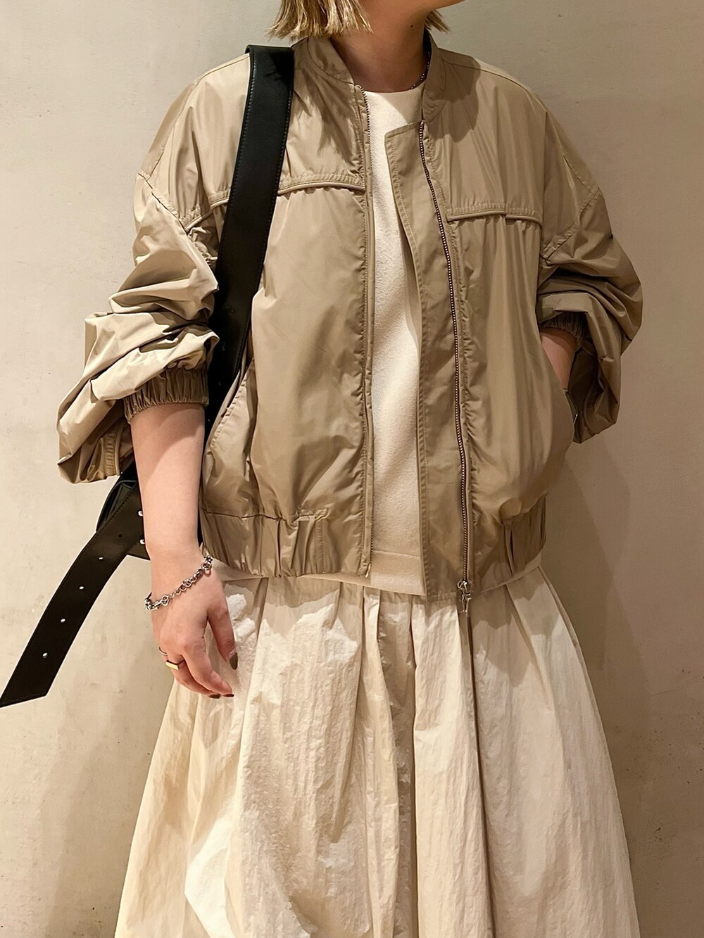 ベージュ系のブルゾン、ベージュ系のワンピース、ブラック系のブーツを着用したレディースの夏コーディネートの4枚目の写真