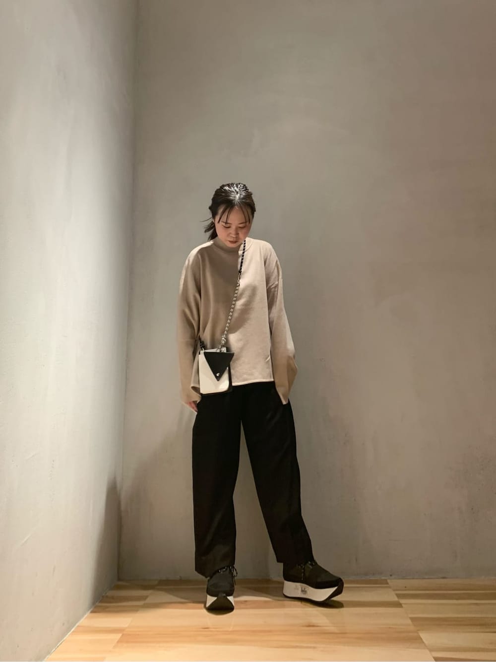 ブラック系のショルダーバッグ、ブラック系のその他パンツ、ベージュ系のニット/セーターを着用したレディースの秋コーディネートの2枚目の写真