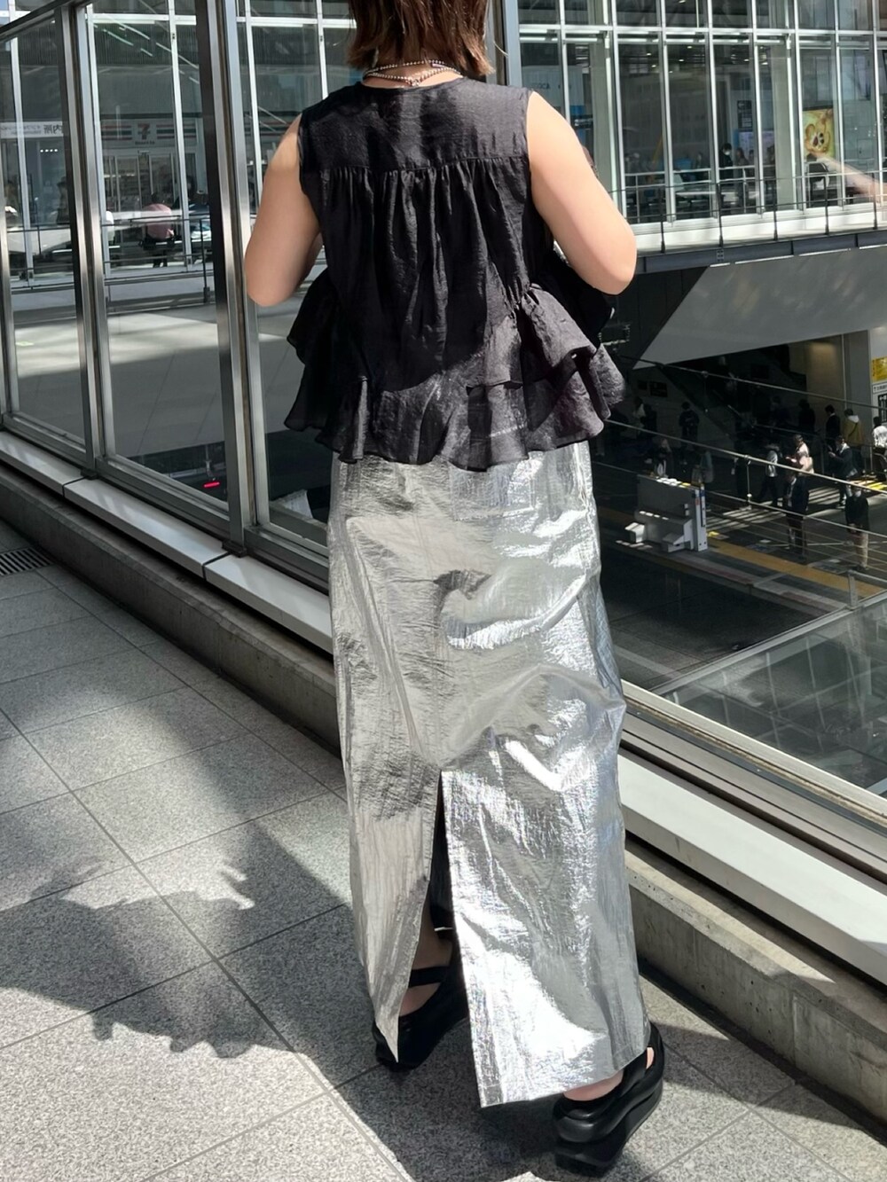 ブラック系のシャツ/ブラウス、シルバー系のスカート、ブラック系のサンダルを着用したレディースの春コーディネートの4枚目の写真