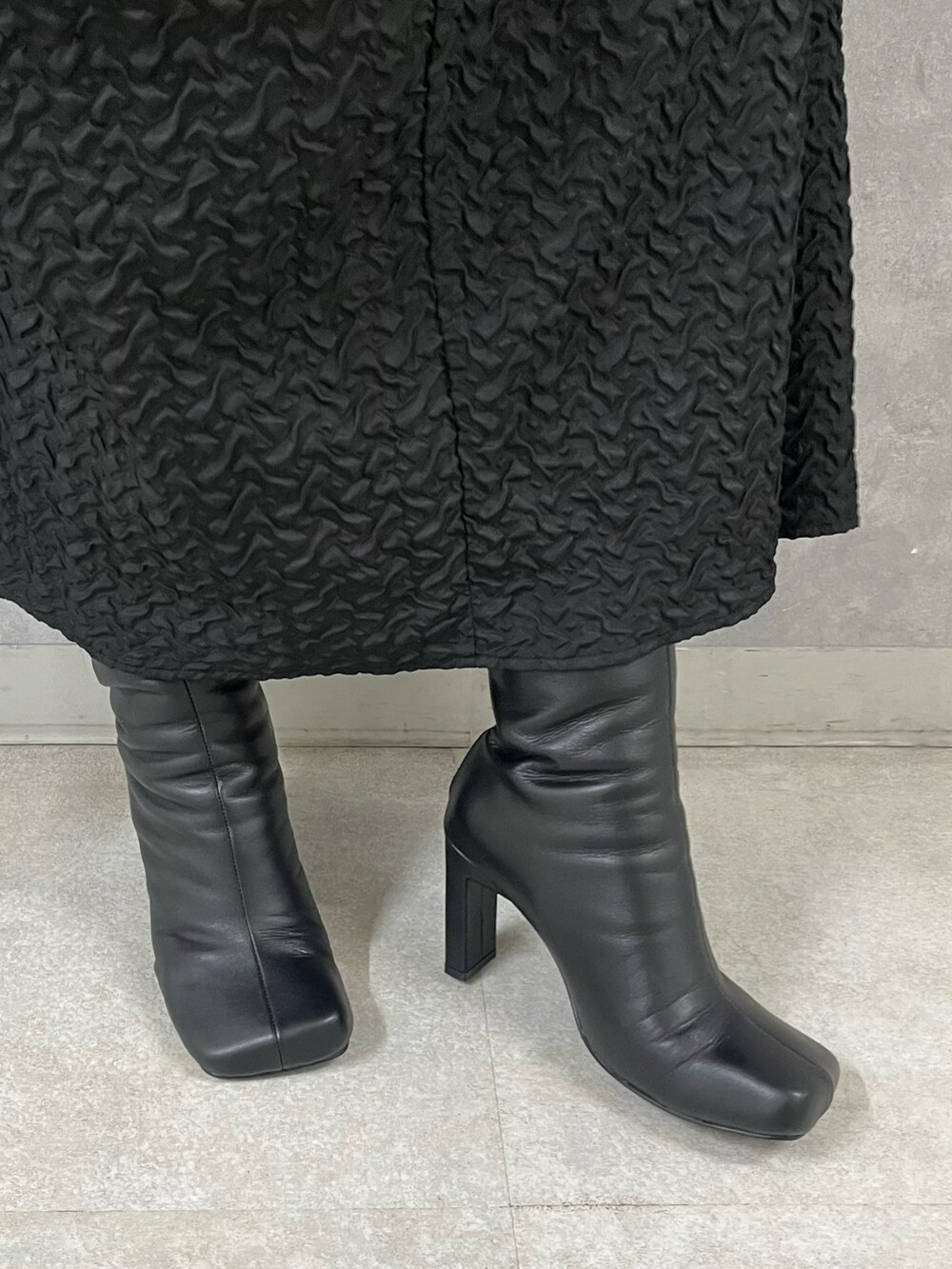 ブラック系のワンピース、ブラック系のブーツを着用したレディースの秋コーディネートの9枚目の写真