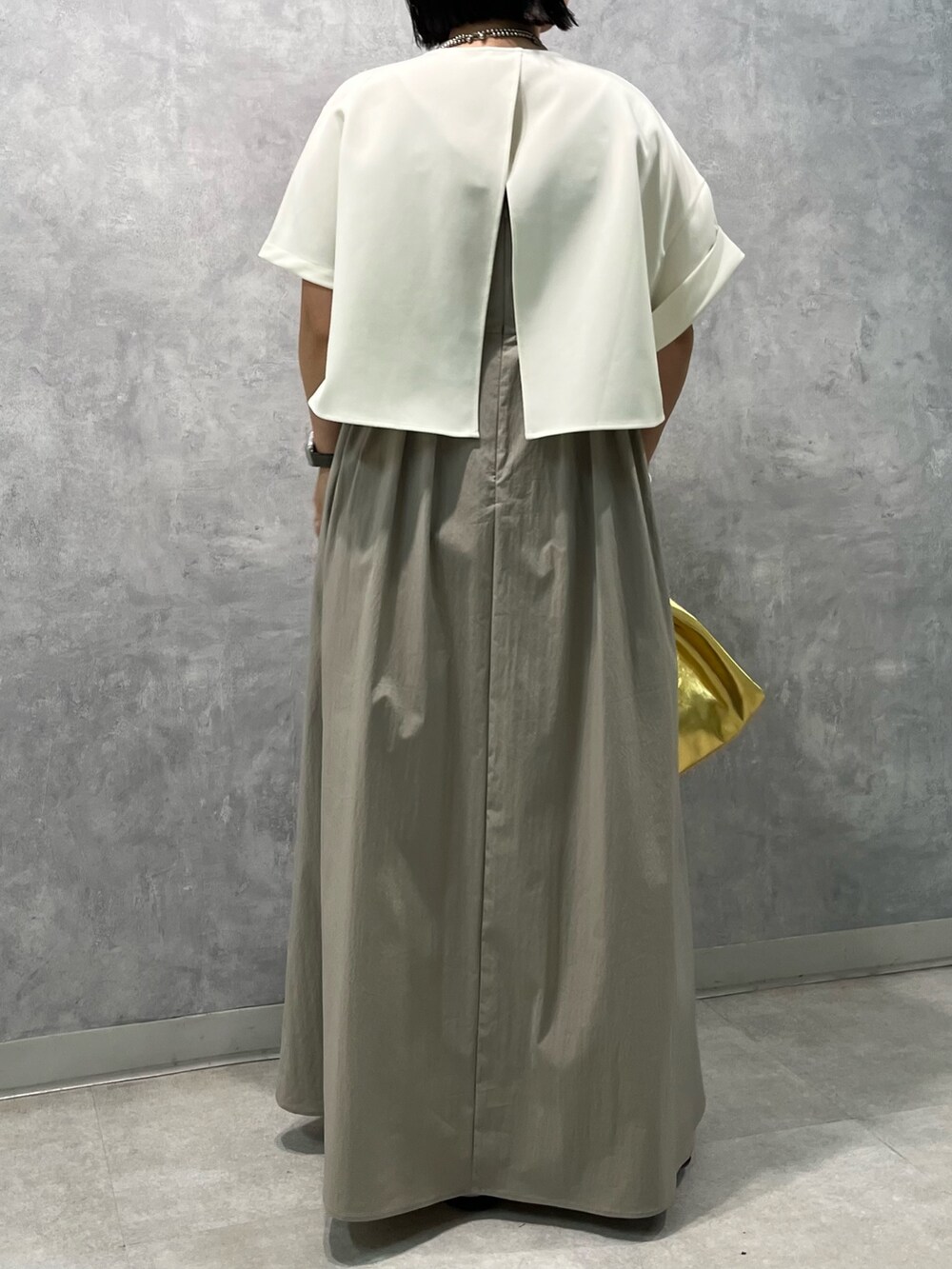 ベージュ系のワンピース、ゴールド系のハンドバッグを着用したレディースの夏コーディネートの4枚目の写真