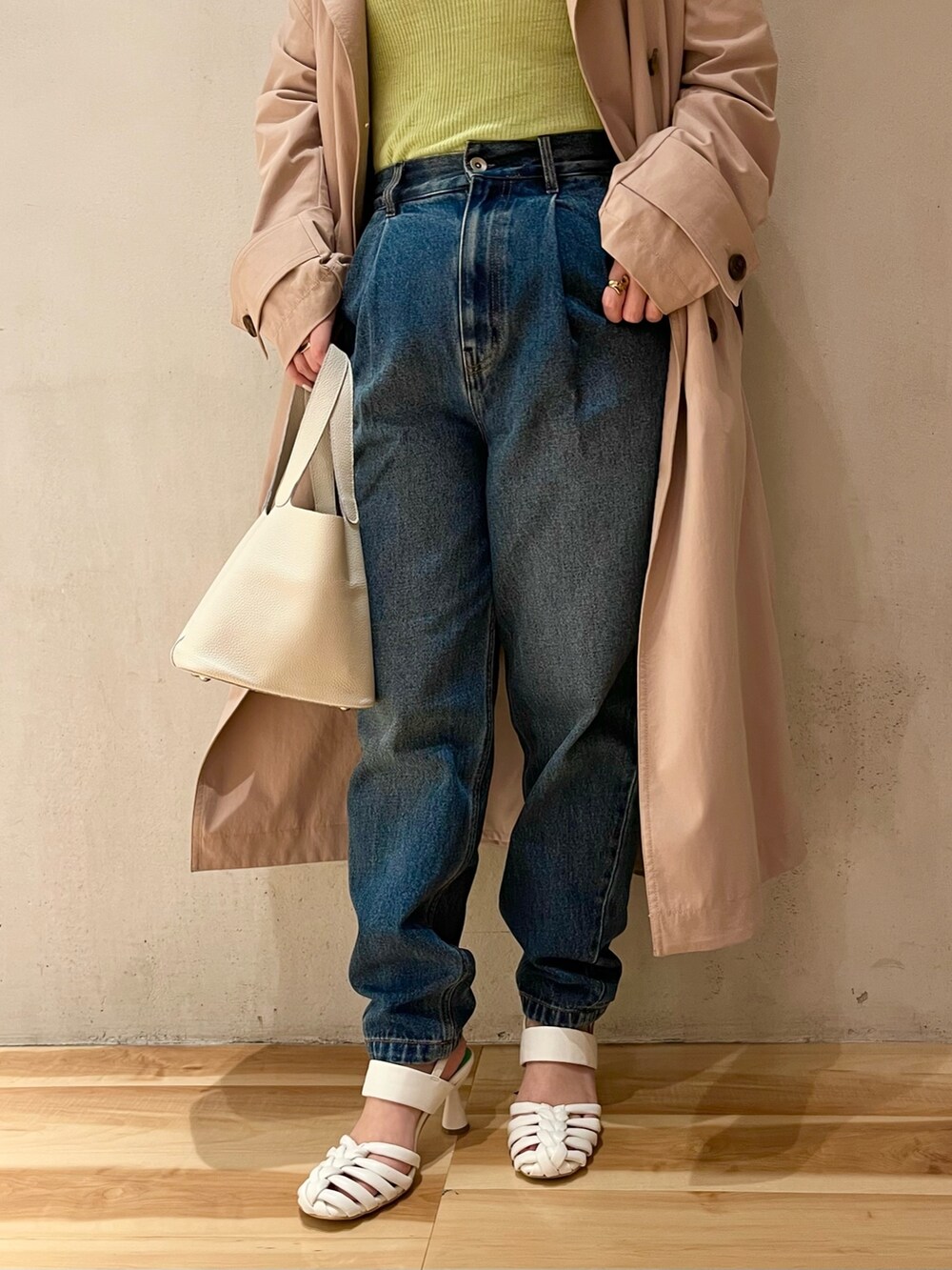 グリーン系のニット/セーター、ベージュ系のトレンチコート、ブルー系のデニムパンツを着用したレディースの冬コーディネートの7枚目の写真